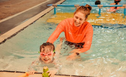 A swimming instructor with a child in the pool